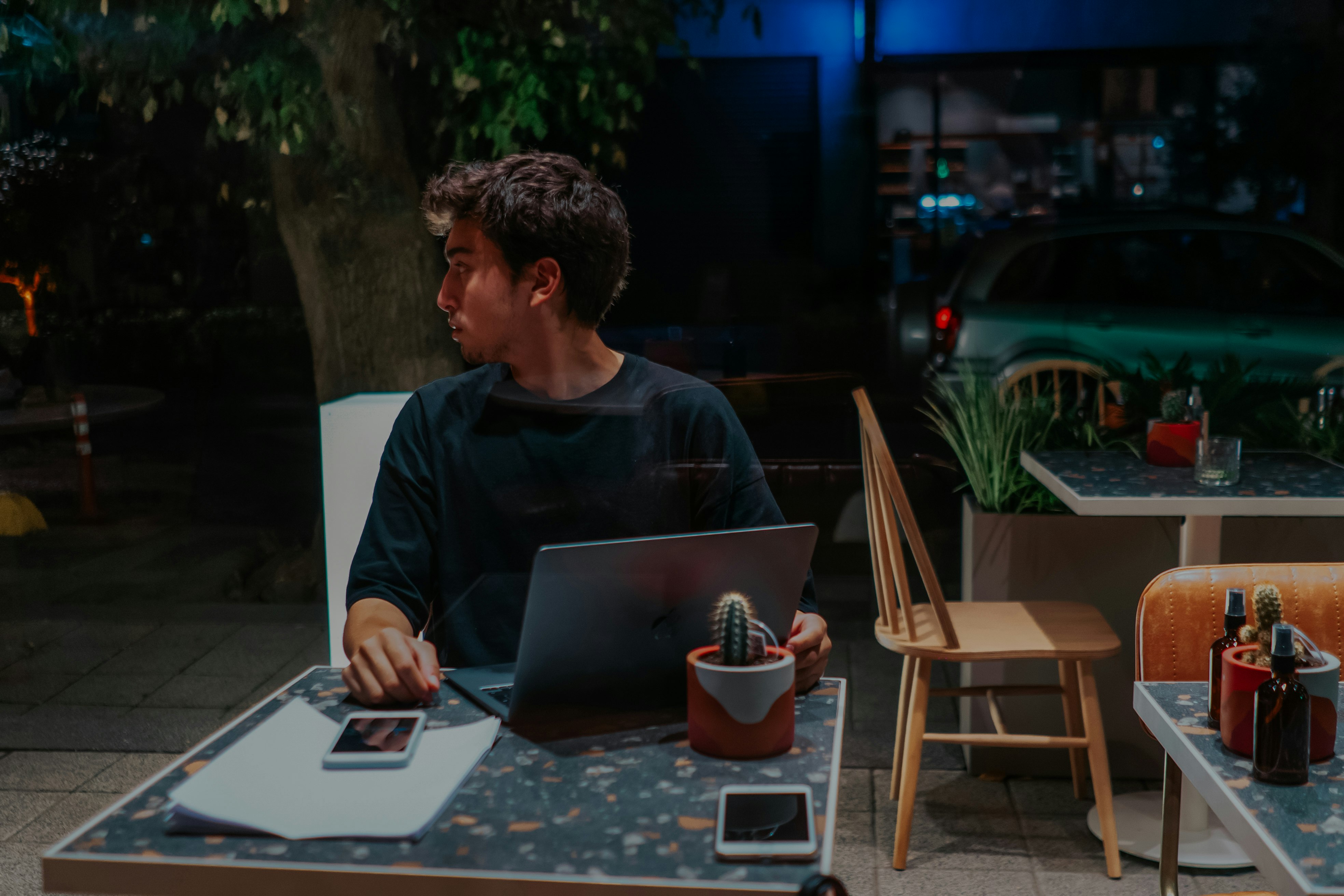 man in black crew neck shirt sitting on chair using macbook